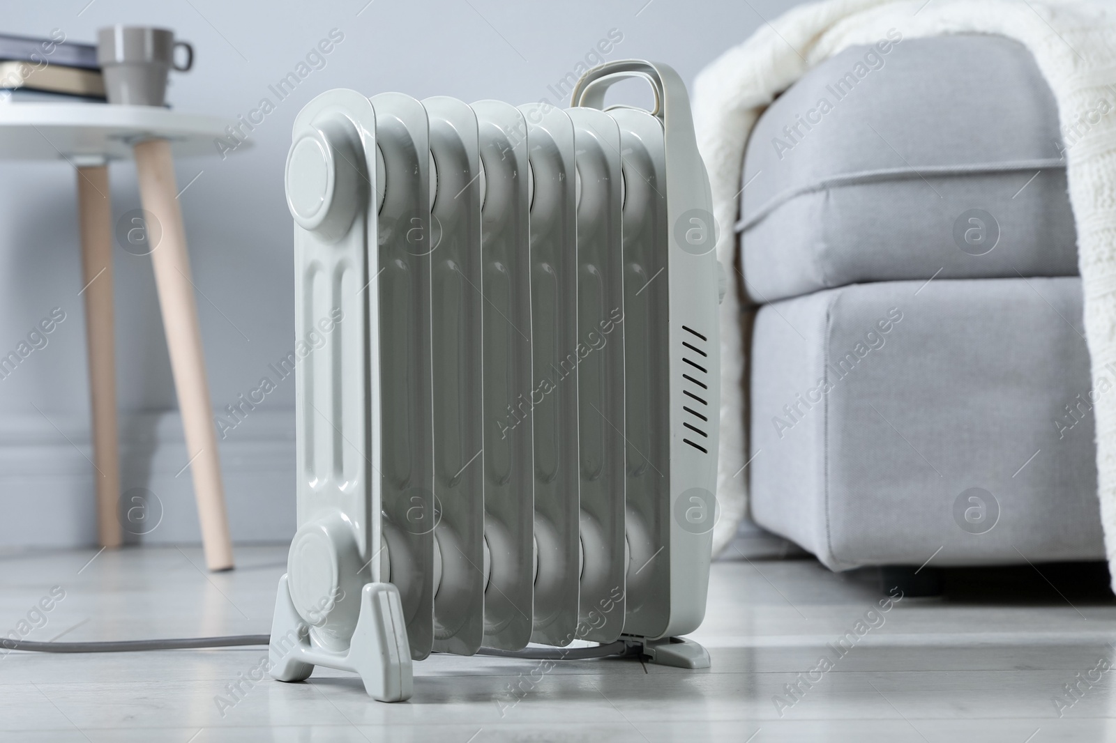 Photo of Electric heater on light wooden floor indoors, closeup