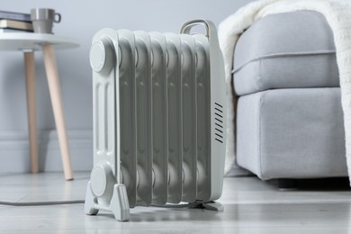 Photo of Electric heater on light wooden floor indoors, closeup