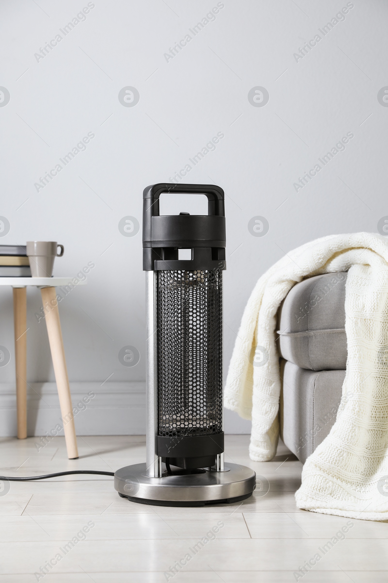 Photo of Electric heater on light wooden floor indoors