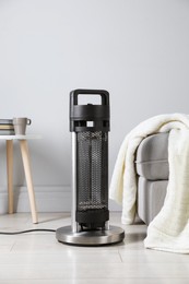 Photo of Electric heater on light wooden floor indoors