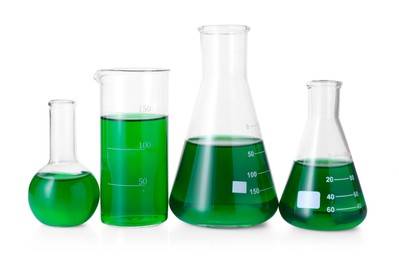 Photo of Different laboratory glassware with green liquid isolated on white