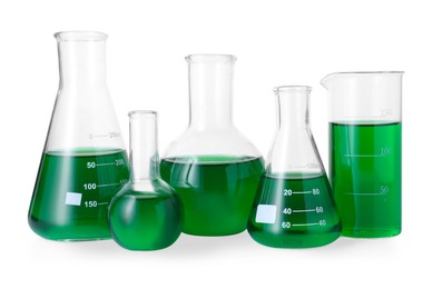 Photo of Different laboratory glassware with green liquid isolated on white