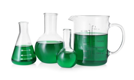 Photo of Different laboratory glassware with green liquid isolated on white