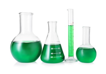 Photo of Different laboratory glassware with green liquid isolated on white