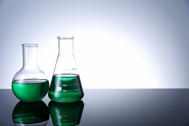 Photo of Different laboratory glassware with green liquid on table against white background. Space for text