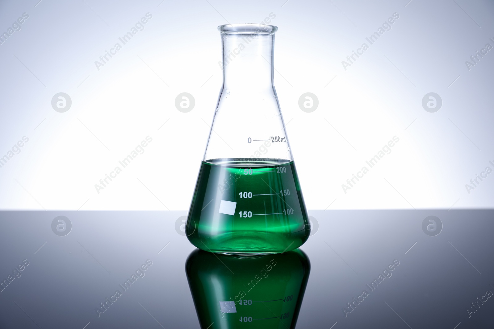 Photo of Flask with green liquid on table against white background