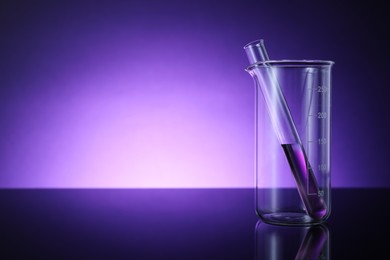 Photo of Beaker and test tube with color liquid on table against violet background. Space for text