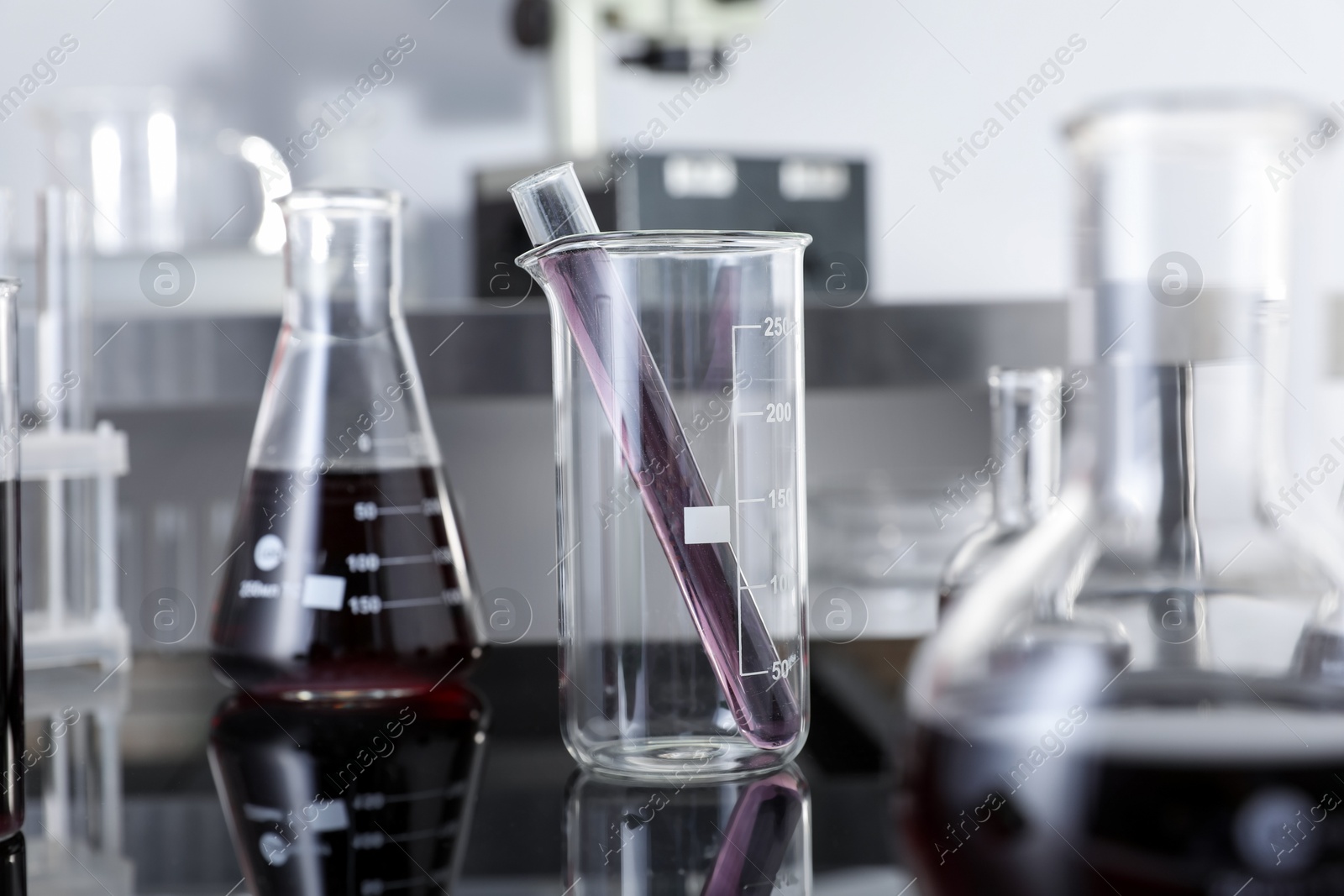 Photo of Different glassware with red liquid on table in laboratory, selective focus