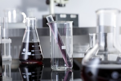 Photo of Different glassware with red liquid on table in laboratory, selective focus