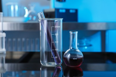 Photo of Different glassware with red liquid on table in laboratory, closeup