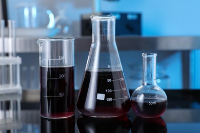 Photo of Different glassware with red liquid on table in laboratory, closeup
