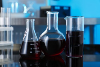 Photo of Different glassware with red liquid on table in laboratory, closeup