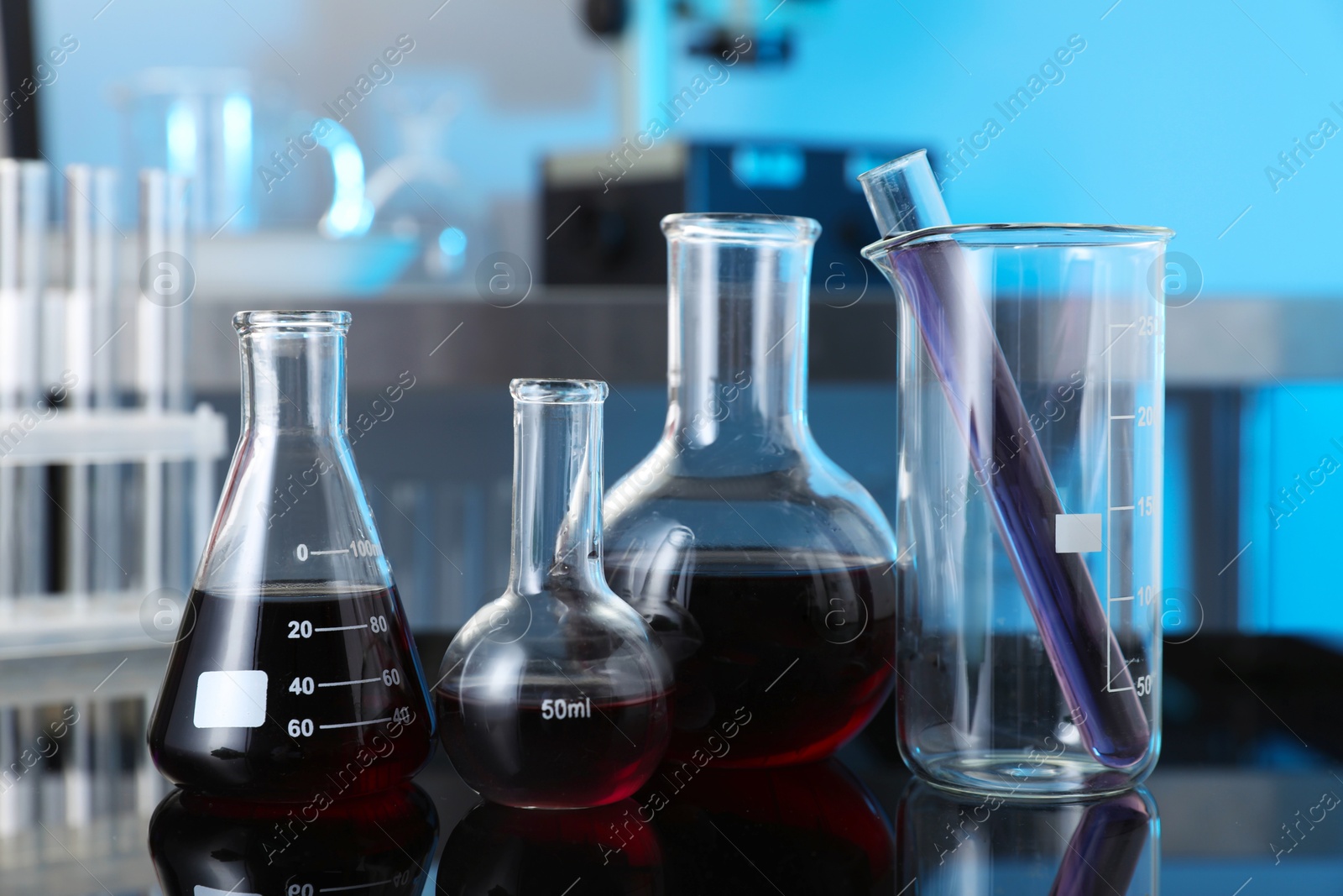 Photo of Different glassware with red liquid on table in laboratory, closeup