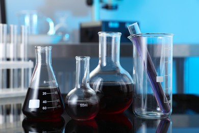 Photo of Different glassware with red liquid on table in laboratory, closeup