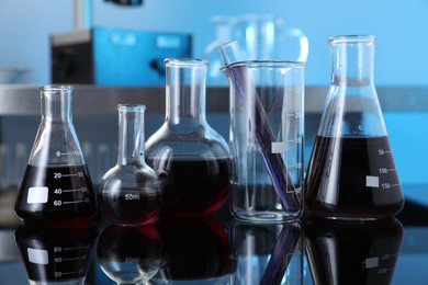 Photo of Different glassware with red liquid on table in laboratory, closeup