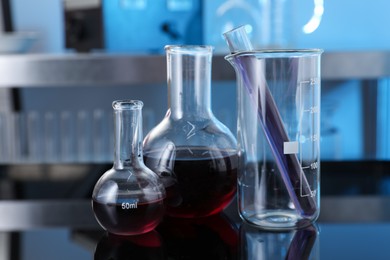 Photo of Different glassware with red liquid on table in laboratory, closeup