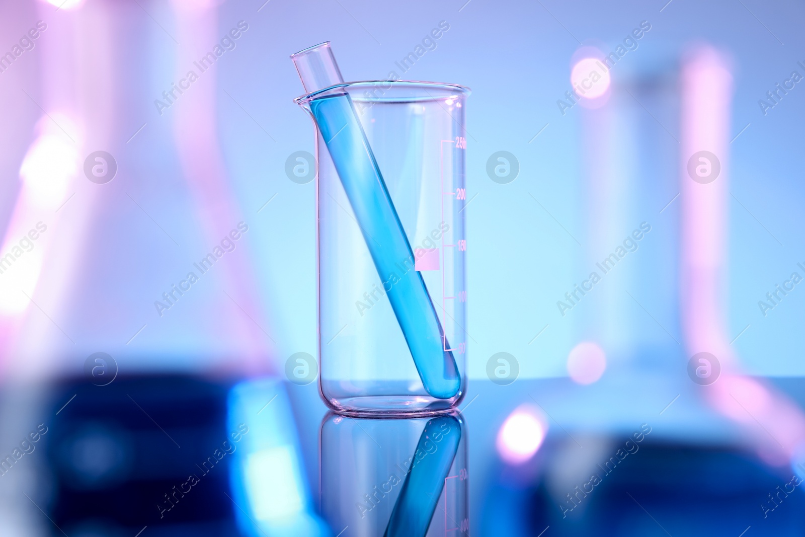 Photo of Different glassware with blue liquid on mirror surface against color background