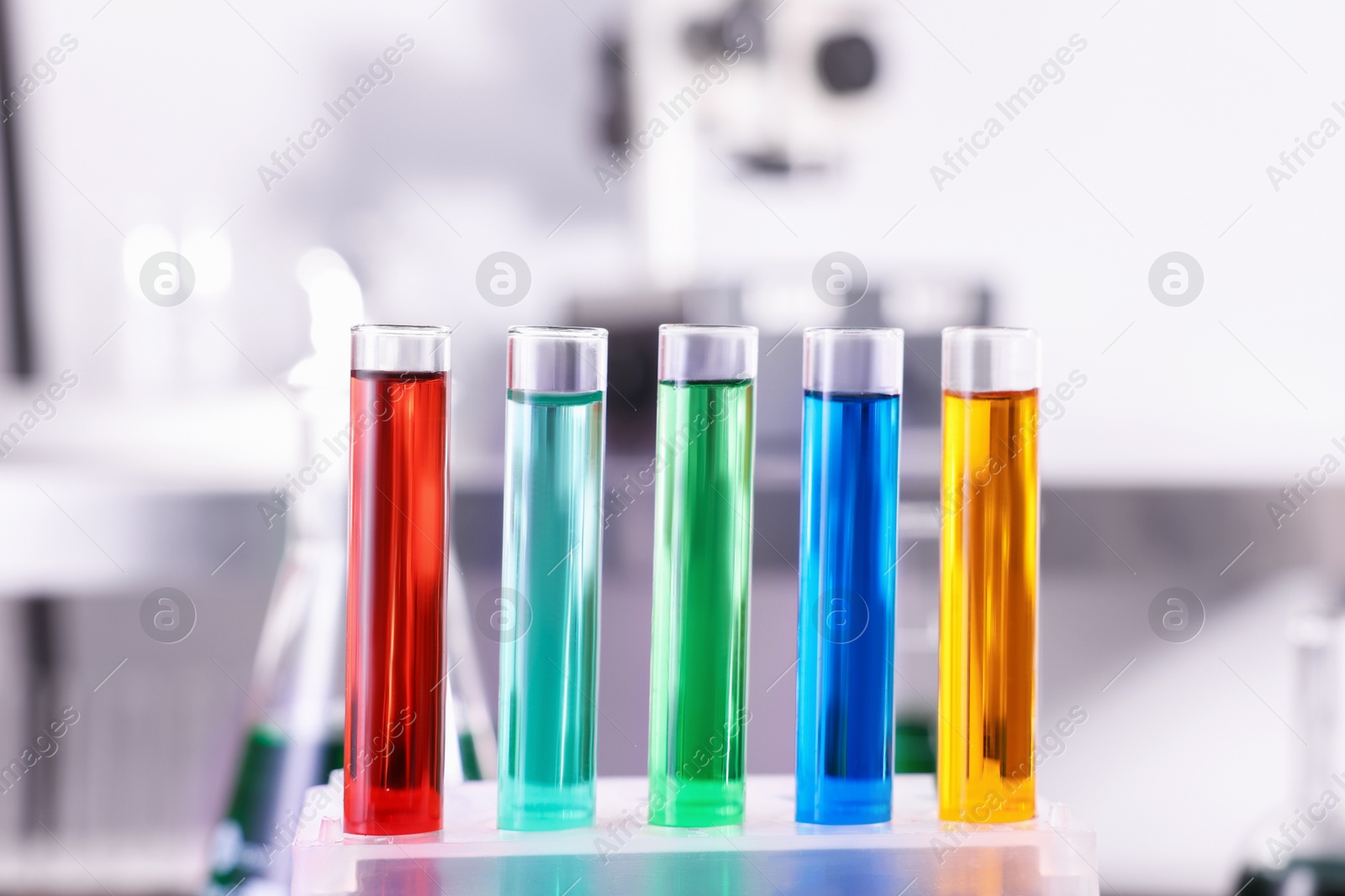 Photo of Test tubes with different colorful liquids on table in laboratory, closeup