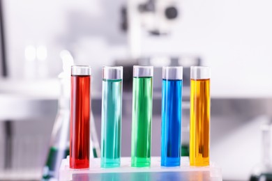 Photo of Test tubes with different colorful liquids on table in laboratory, closeup