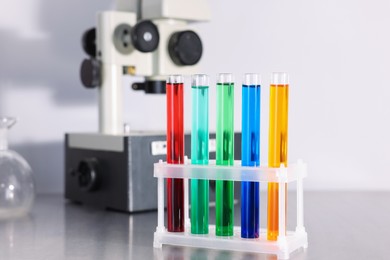 Photo of Test tubes with different colorful liquids on table in laboratory, closeup