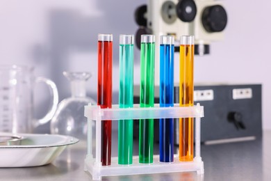 Photo of Test tubes and other glassware with different colorful liquids on table in laboratory, closeup