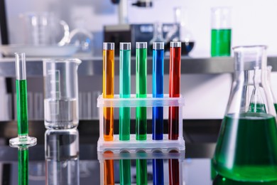 Photo of Test tubes and other glassware with different colorful liquids on table in laboratory, closeup
