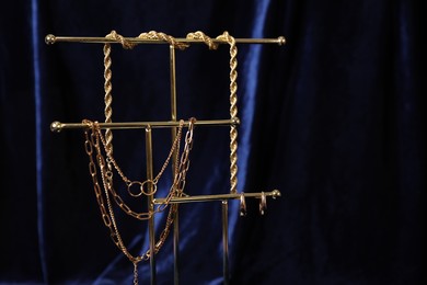 Photo of Stylish presentation of beautiful gold jewelry against dark blue fabric, closeup. Space for text