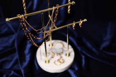 Photo of Stylish presentation of beautiful gold jewelry against dark blue fabric, closeup. Space for text
