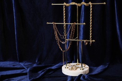 Photo of Stylish presentation of beautiful gold jewelry against dark blue fabric, space for text