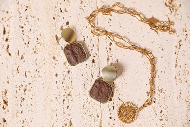 Photo of Beautiful gold jewelry on beige textured surface, flat lay