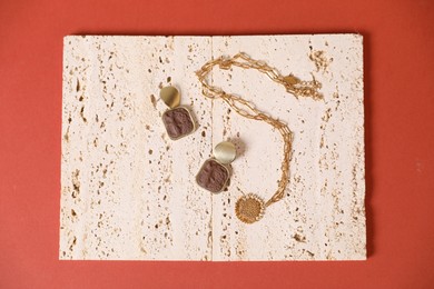 Photo of Beautiful gold jewelry on red-brown background, top view