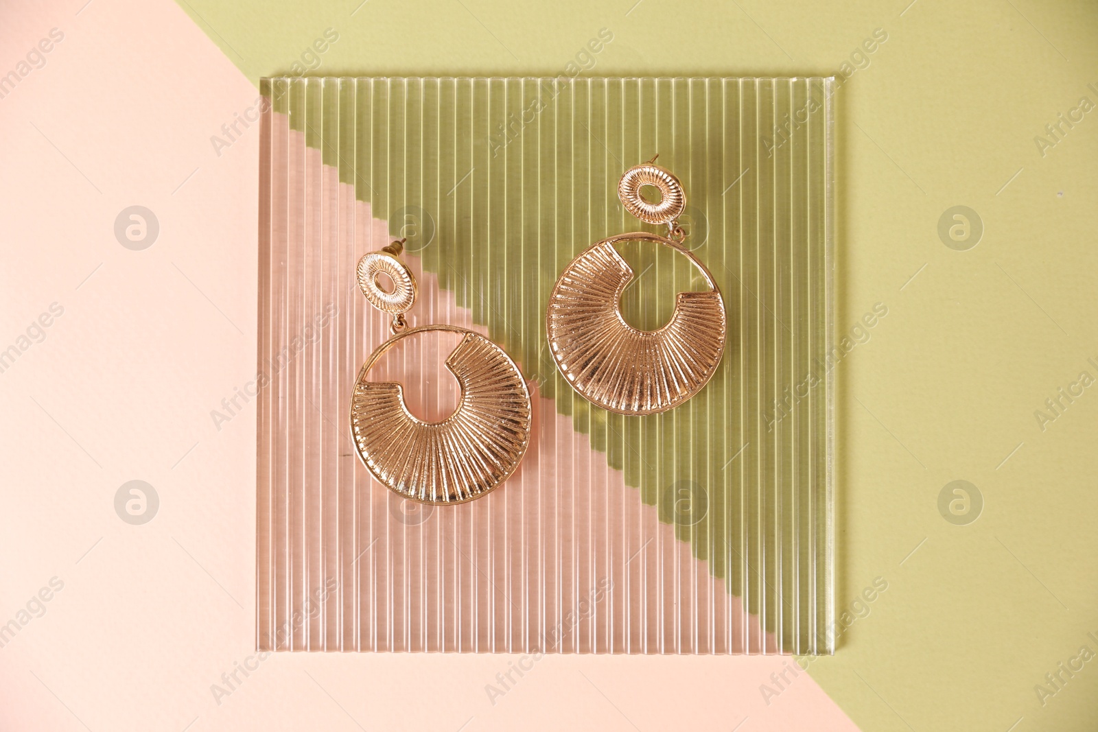 Photo of Beautiful gold earrings on color background, top view