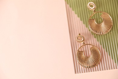 Photo of Beautiful gold earrings on beige background, top view. Space for text