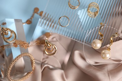 Photo of Stylish presentation of beautiful gold jewelry on light blue background, flat lay