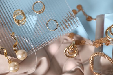 Photo of Stylish presentation of beautiful gold jewelry on light blue background, flat lay