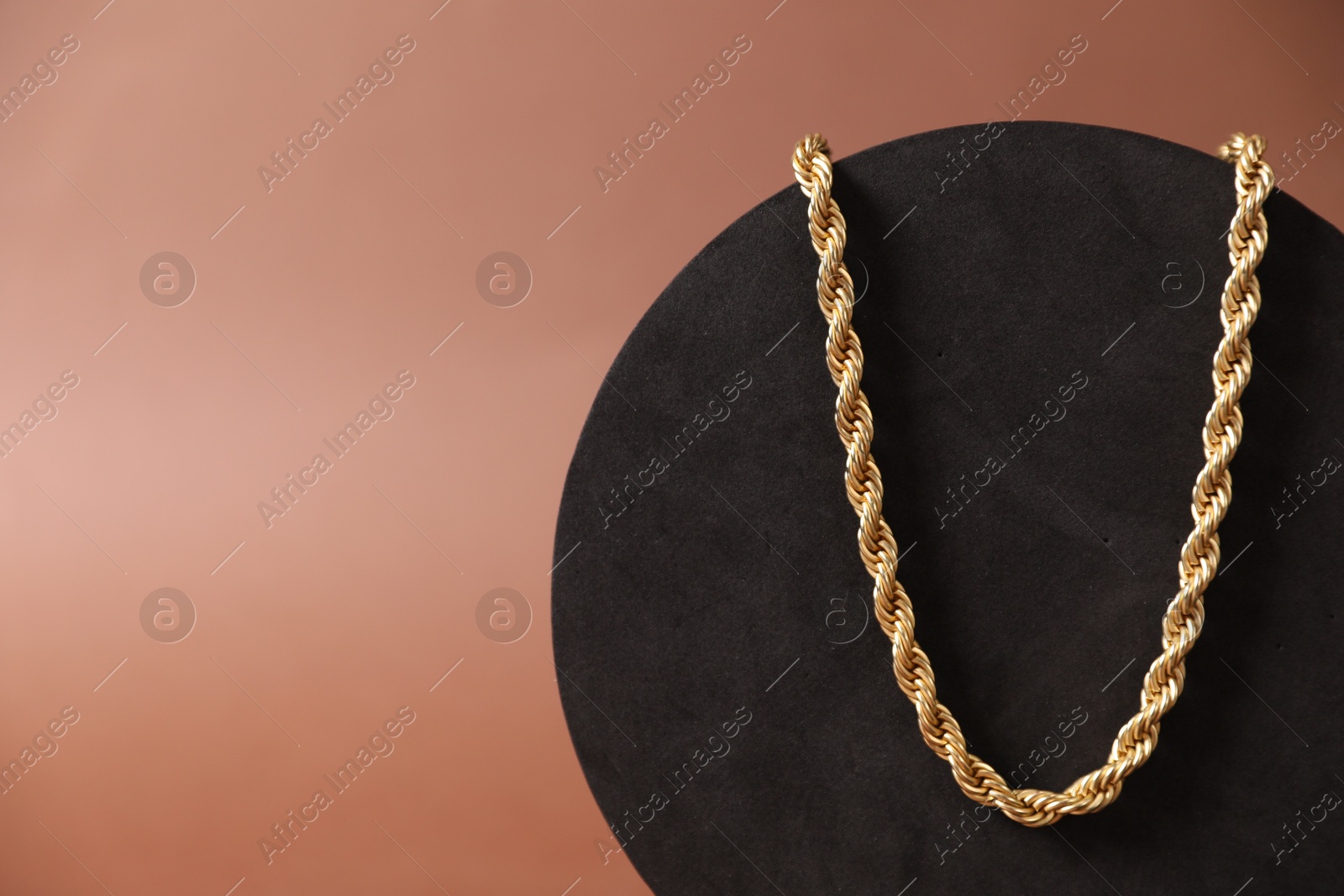 Photo of Beautiful gold necklace on brown background, closeup. Space for text