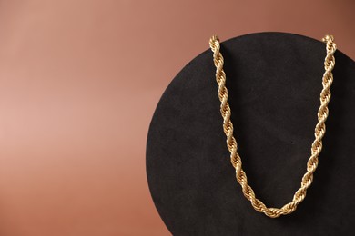 Photo of Beautiful gold necklace on brown background, closeup. Space for text
