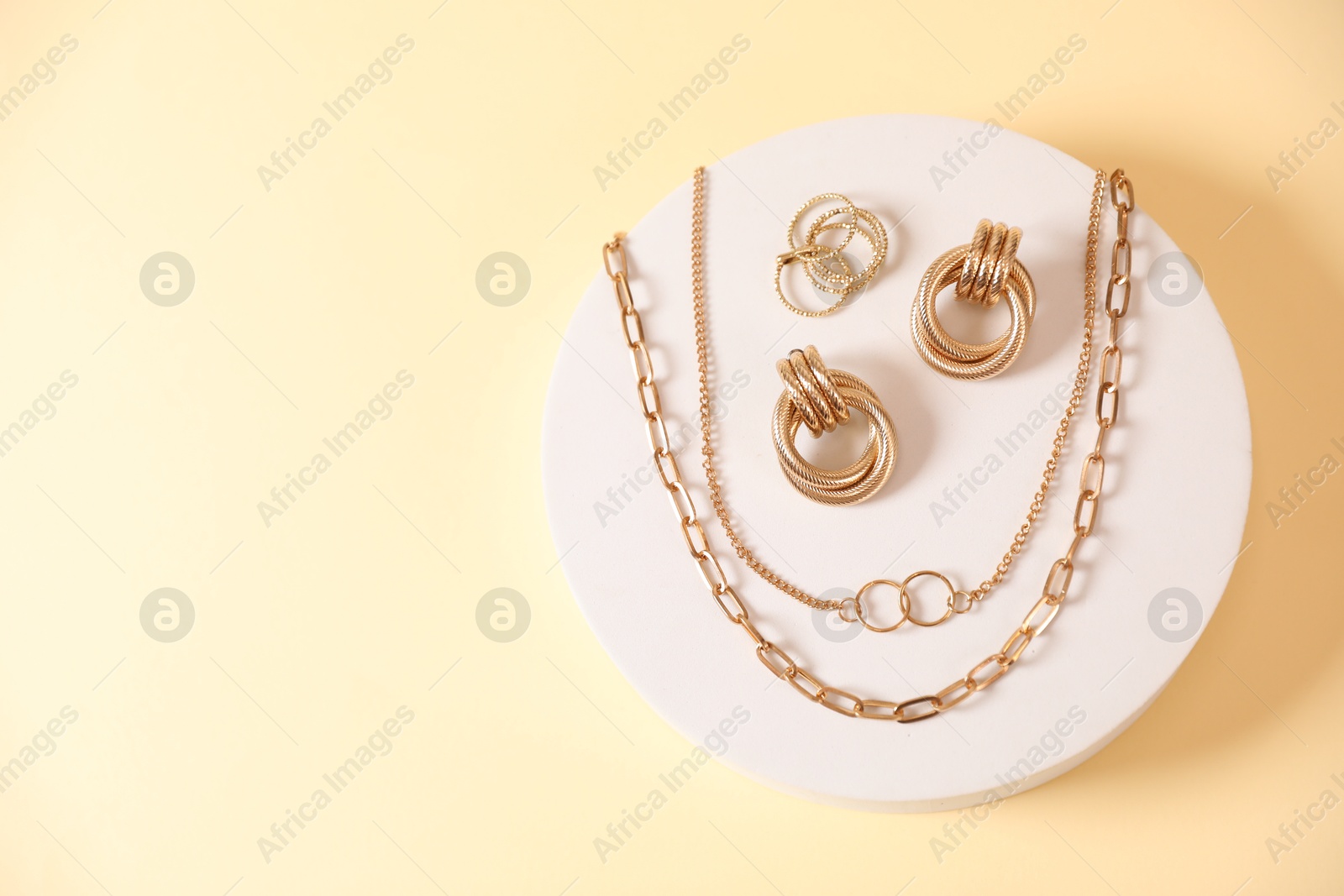 Photo of Beautiful gold jewelry on beige background, top view. Space for text