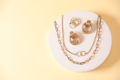 Photo of Beautiful gold jewelry on beige background, top view. Space for text