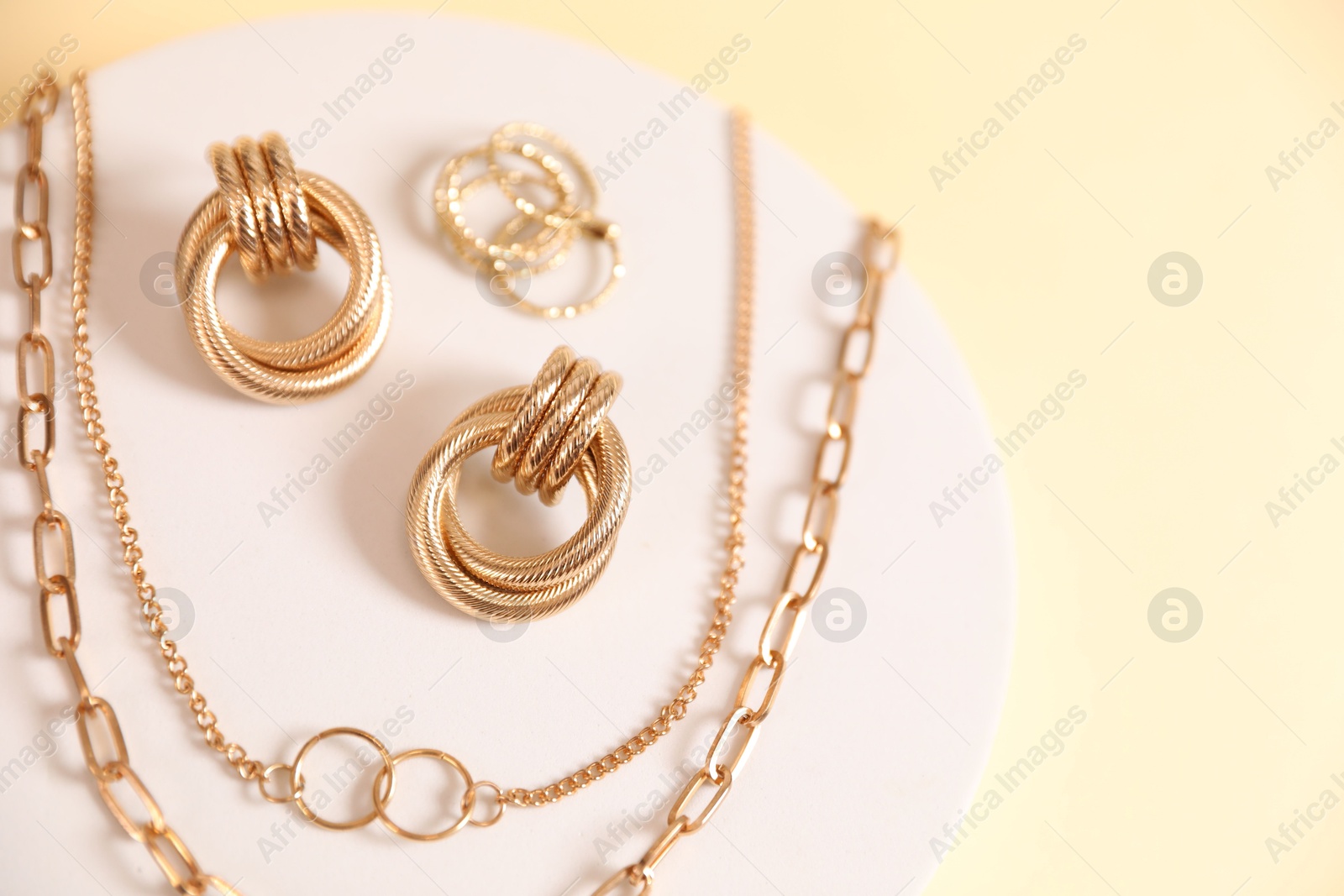 Photo of Beautiful gold jewelry on beige background, top view