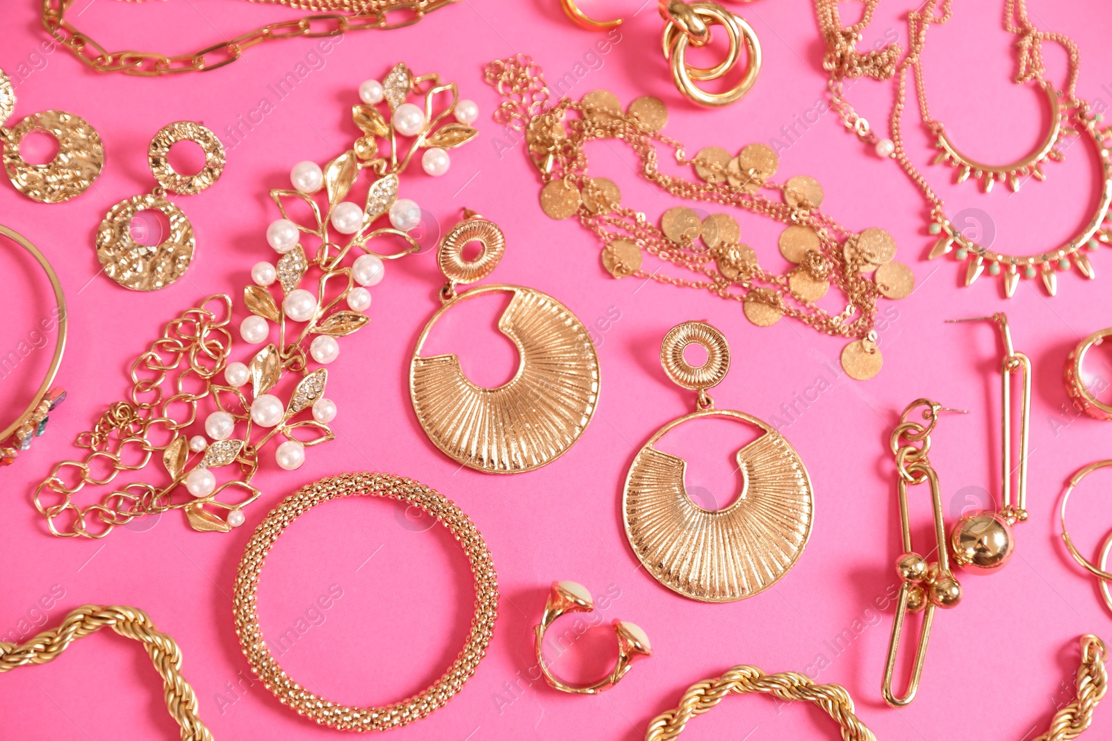 Photo of Beautiful gold jewelry on pink background, flat lay