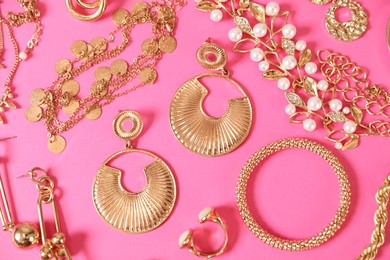 Photo of Beautiful gold jewelry on pink background, flat lay