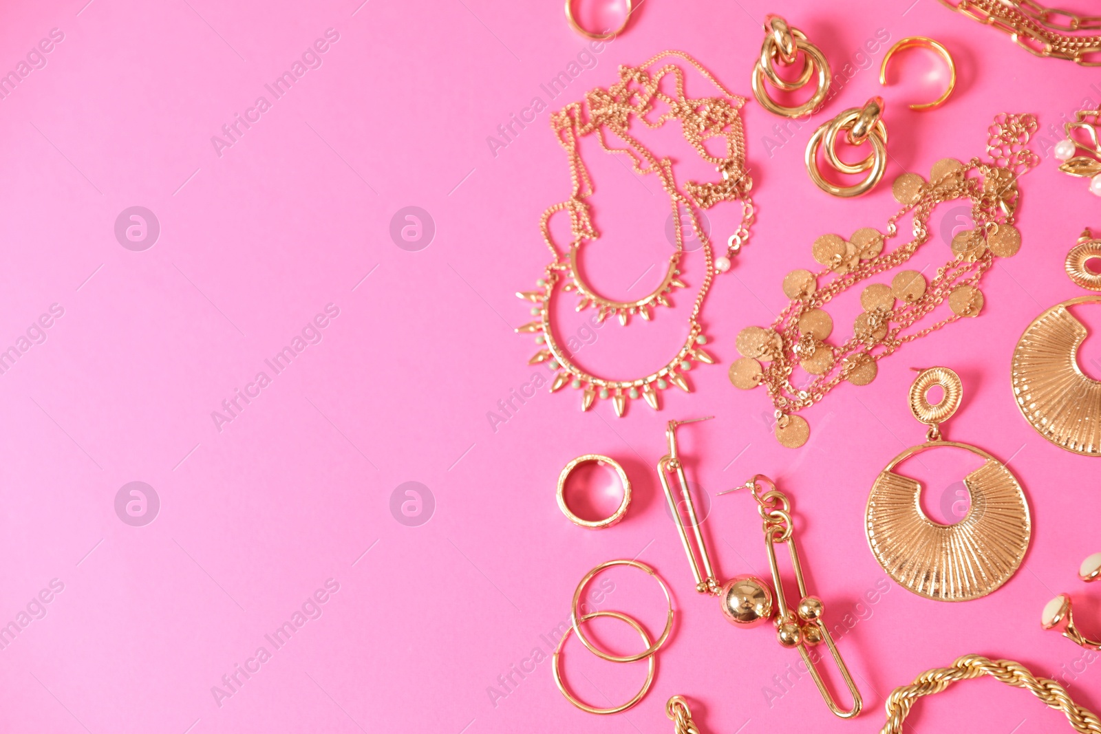 Photo of Beautiful gold jewelry on pink background, flat lay. Space for text
