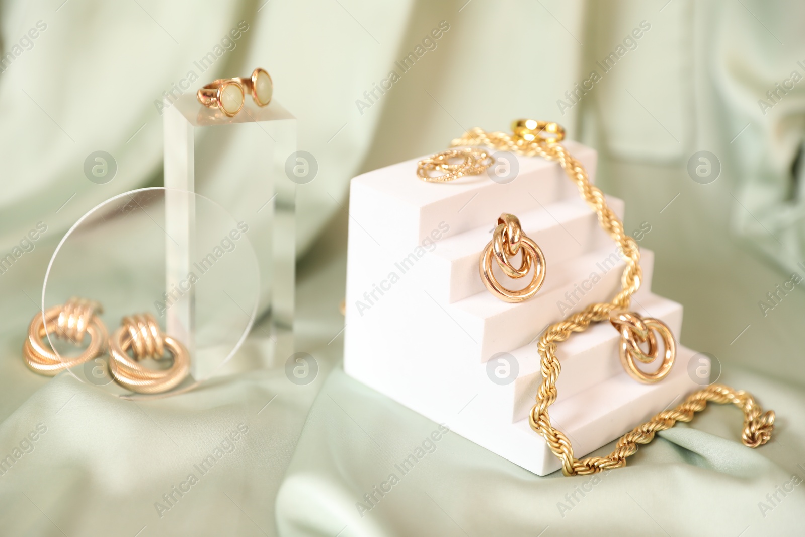 Photo of Stylish presentation of beautiful gold jewelry on silk cloth, closeup