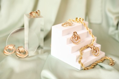 Photo of Stylish presentation of beautiful gold jewelry on silk cloth, closeup