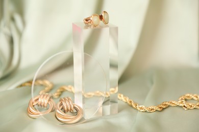 Photo of Stylish presentation of beautiful gold jewelry on silk cloth, closeup