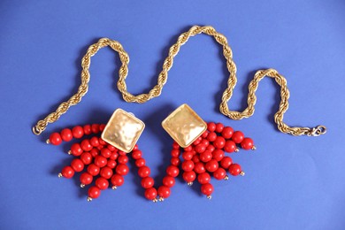 Photo of Beautiful gold jewelry on blue background, flat lay