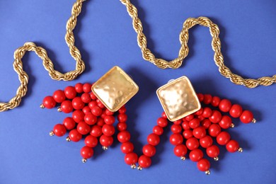 Photo of Beautiful gold jewelry on blue background, flat lay