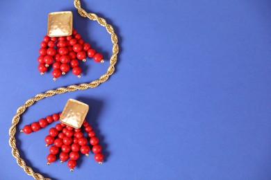 Photo of Beautiful gold jewelry on blue background, flat lay. Space for text