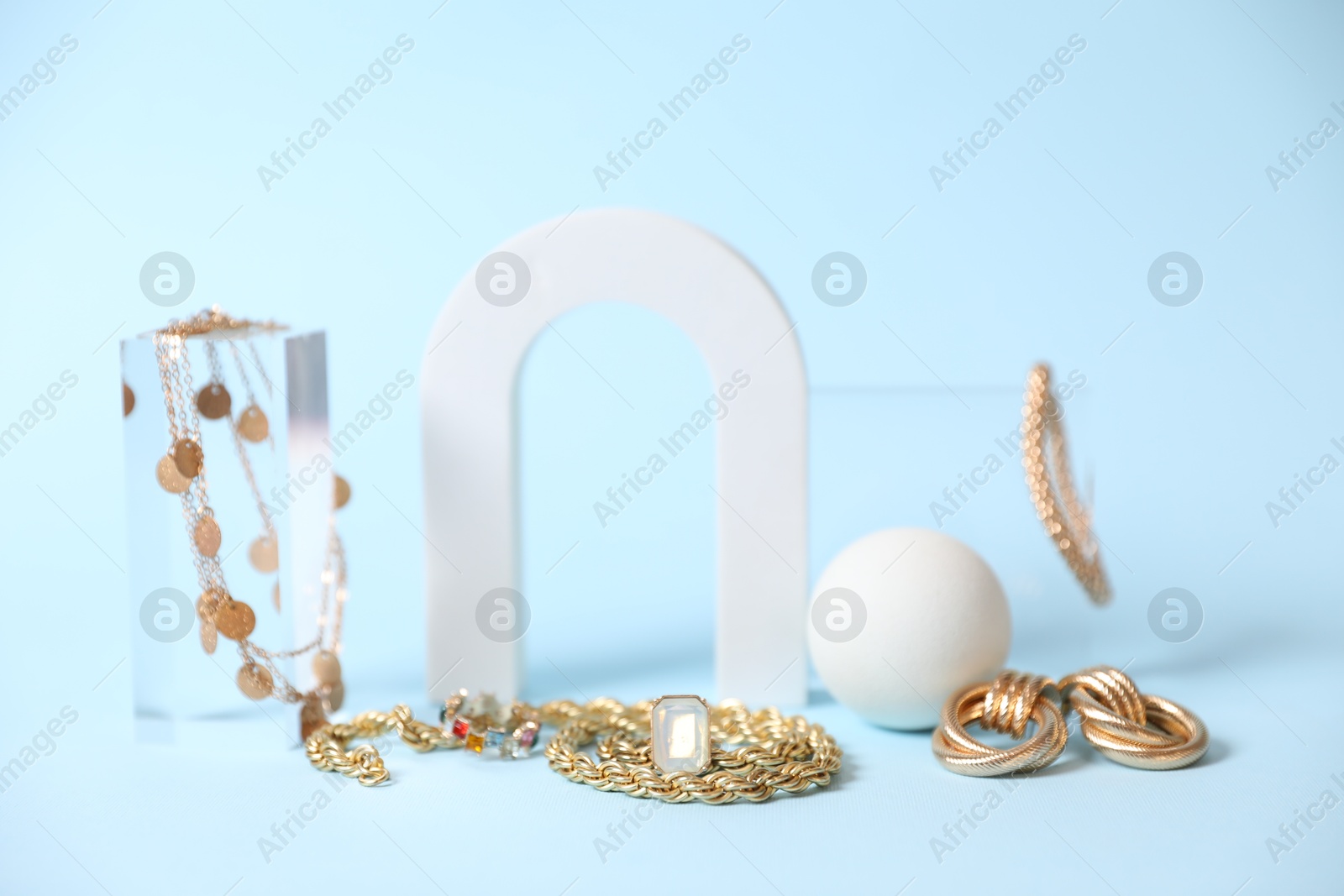 Photo of Stylish presentation of beautiful gold jewelry on light blue background, closeup